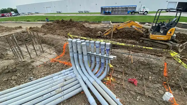 A labeled duct bank sweeping out of a trench into a strut rack, excavator behind