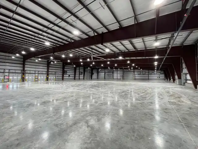 A finished, fully lit warehouse with high-bay LEDs, HVLS fans, polished slab, dock doors